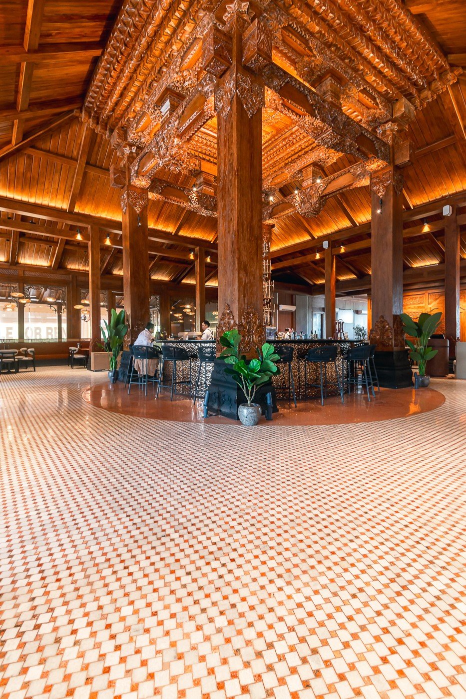 Beautiful interior of a wooden restaurant with ornate ceiling and patterned tile flooring.