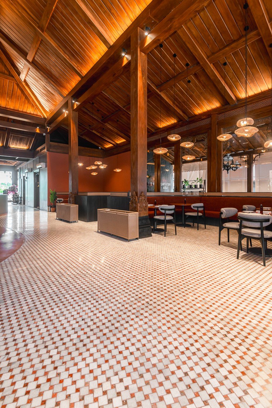 Modern cafe interior with wooden ceiling, pendant lights, and tiled floor. Cozy seating and stylish design.