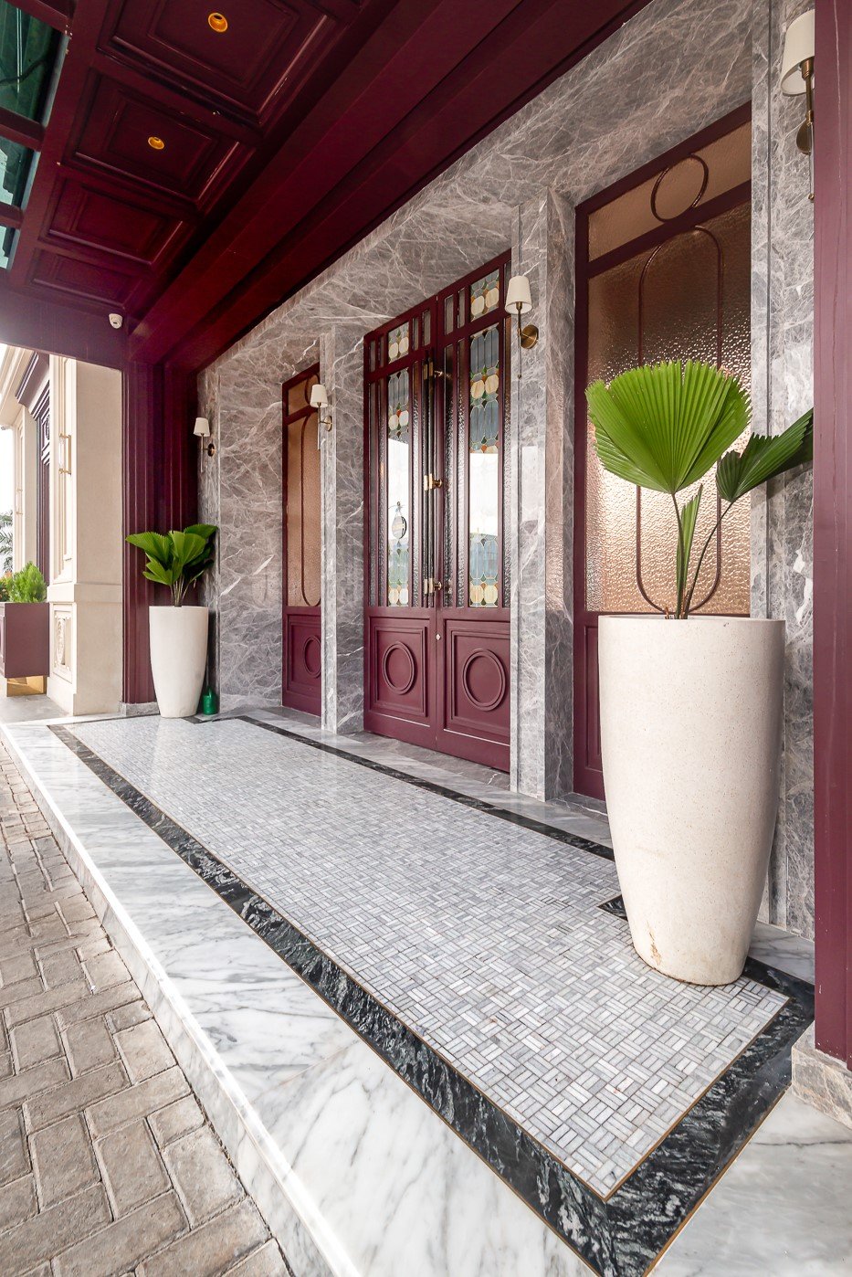 Elegant stone entrance with decorative doors and potted plants enhancing a luxurious architectural design.