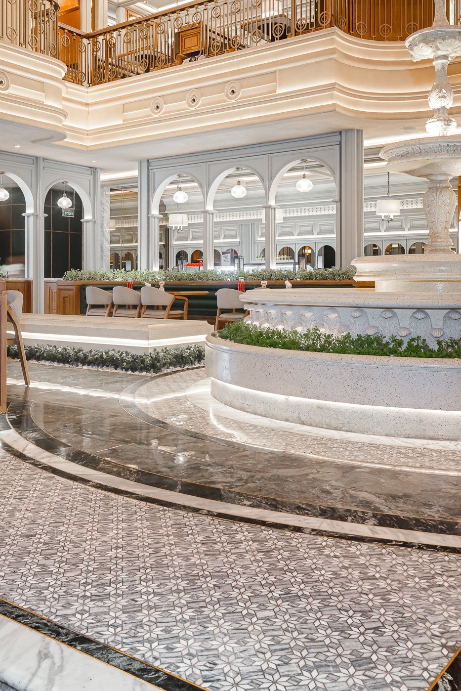 Elegant indoor space with marble floors, decorative arches, and a central fountain in a stylish upscale setting.